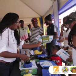 Bridgette Barrett, Community animator for the Adaptation Programme and Financing Mechanism (AP&FM) tells visitors to the booth about the project activities to help residents of the Bullhead and surrounding communities adapt to climate change. climate change